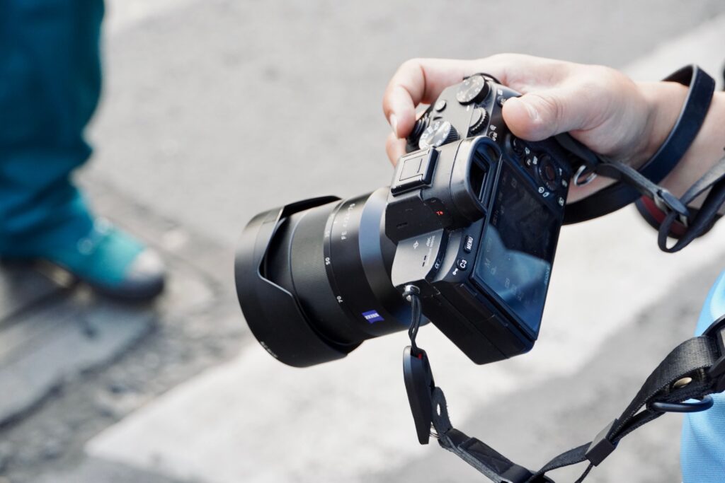Photographer holding a camera with a lens outdoors, detailed shot.