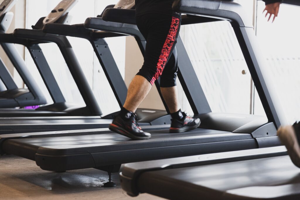 無人ビジネスとは? A person walking on a treadmill in a modern gym setting, focusing on fitness.