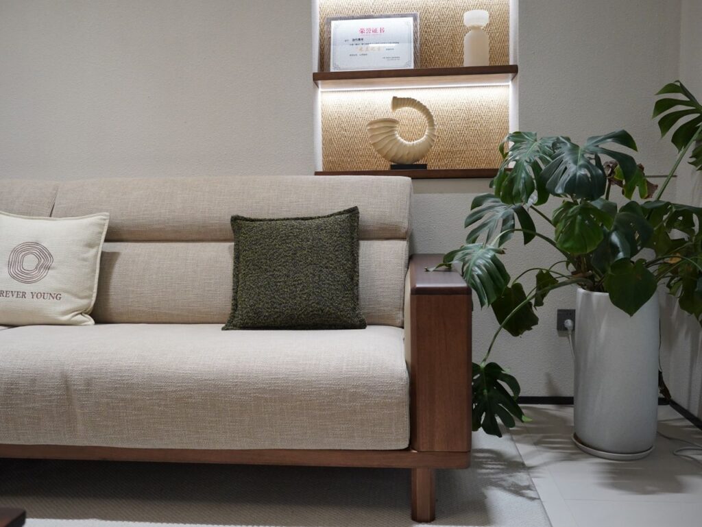 A cozy modern living room featuring a beige sofa, decorative pillows, a Monstera plant, and stylish shelving.