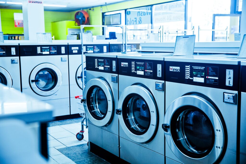 無人ビジネスとは? Contemporary laundromat showcasing a row of industrial washing machines for public use.