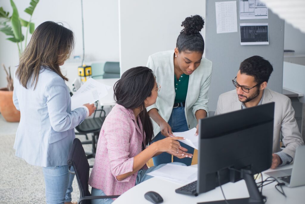 300万円以下でできる無人ビジネス一覧 A diverse team engaged in a lively discussion in a modern office setting, fostering collaboration and teamwork.
